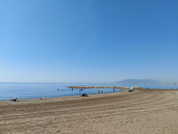 Ein weiter Sandstrand mit blauem, klarem Himmel.