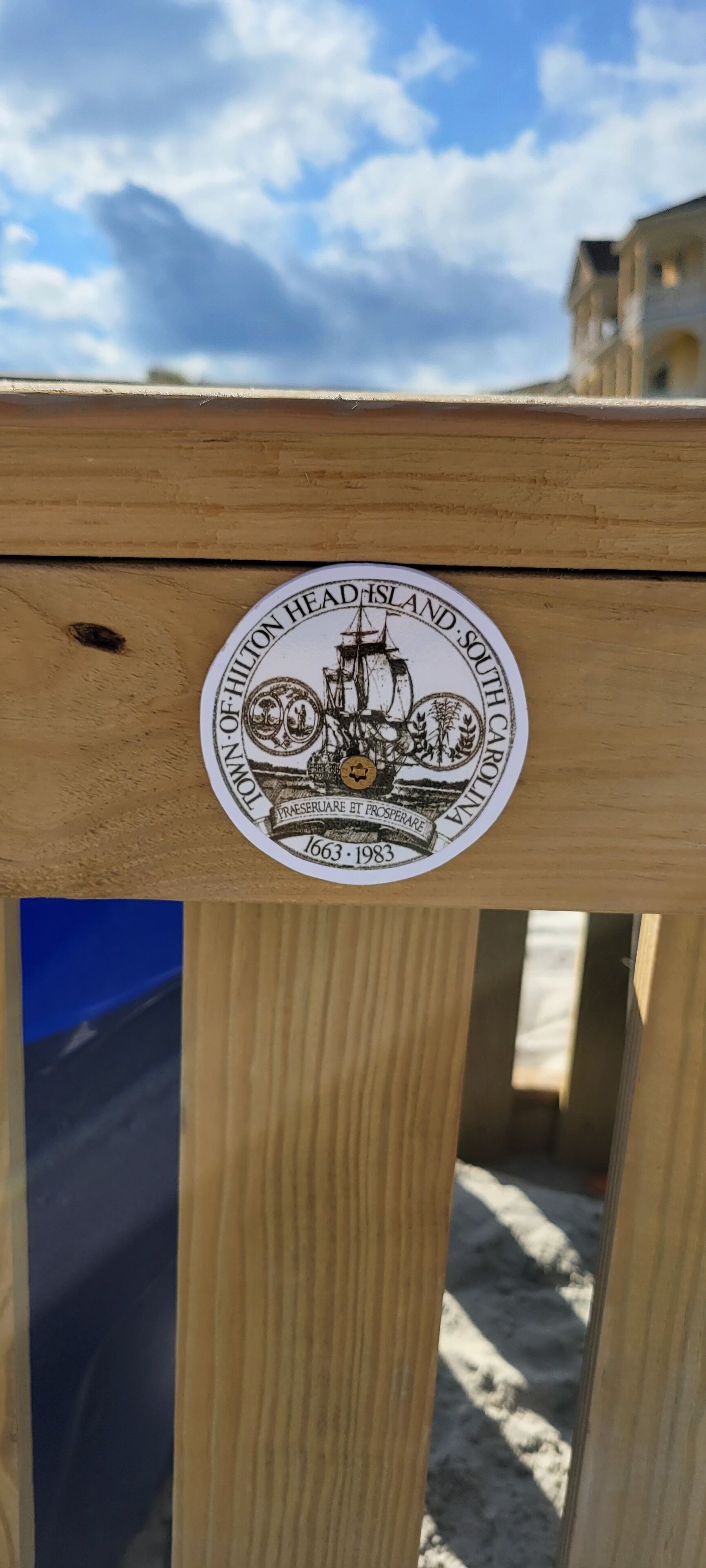 Puinen terassi, jossa on pyöreä tarra, jossa on kuvattuna laiva ja teksti.
