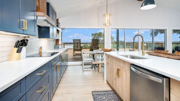 A modern kitchen with a large island, stainless steel appliances, and a view of the outdoors.