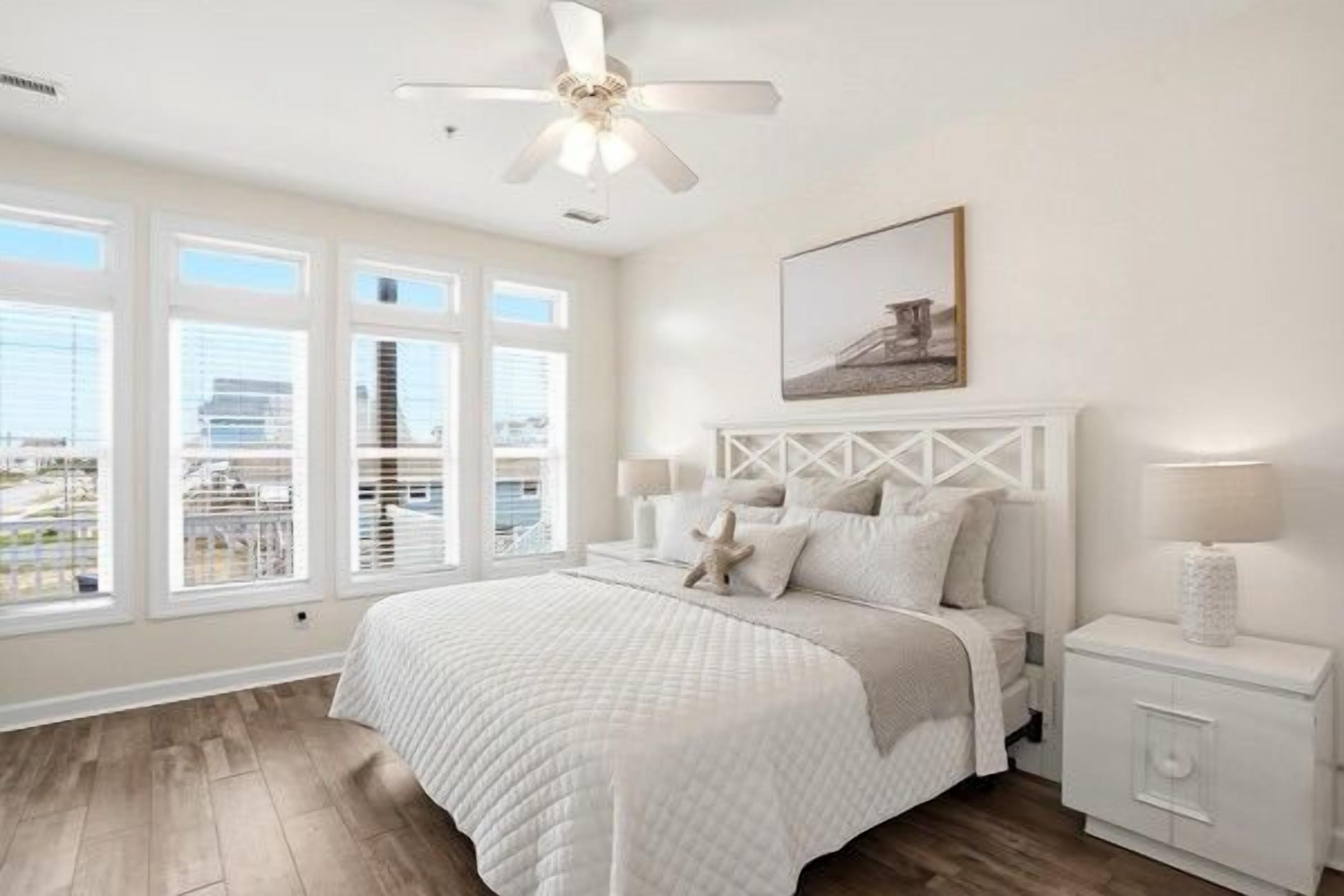 A bedroom with a bed, a nightstand, a ceiling fan, and a window with blinds.