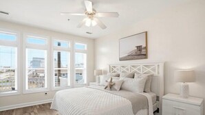 A bedroom with a bed, a nightstand, a ceiling fan, and a window with blinds. - Townhome w/ Pool & Water Views/ Sleeps 12 (Surf City)