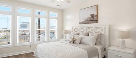 A bedroom with a bed, a nightstand, a ceiling fan, and a window with blinds.