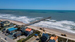 A coastal town with a pier extending into the sea, houses along the beach, and a clear sky. - Townhome w/ Pool & Water Views/ Sleeps 12 (Surf City)