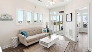 A living room with a sofa, coffee table, and decorative items. - Townhome w/ Pool & Water Views/ Sleeps 12 (Surf City)