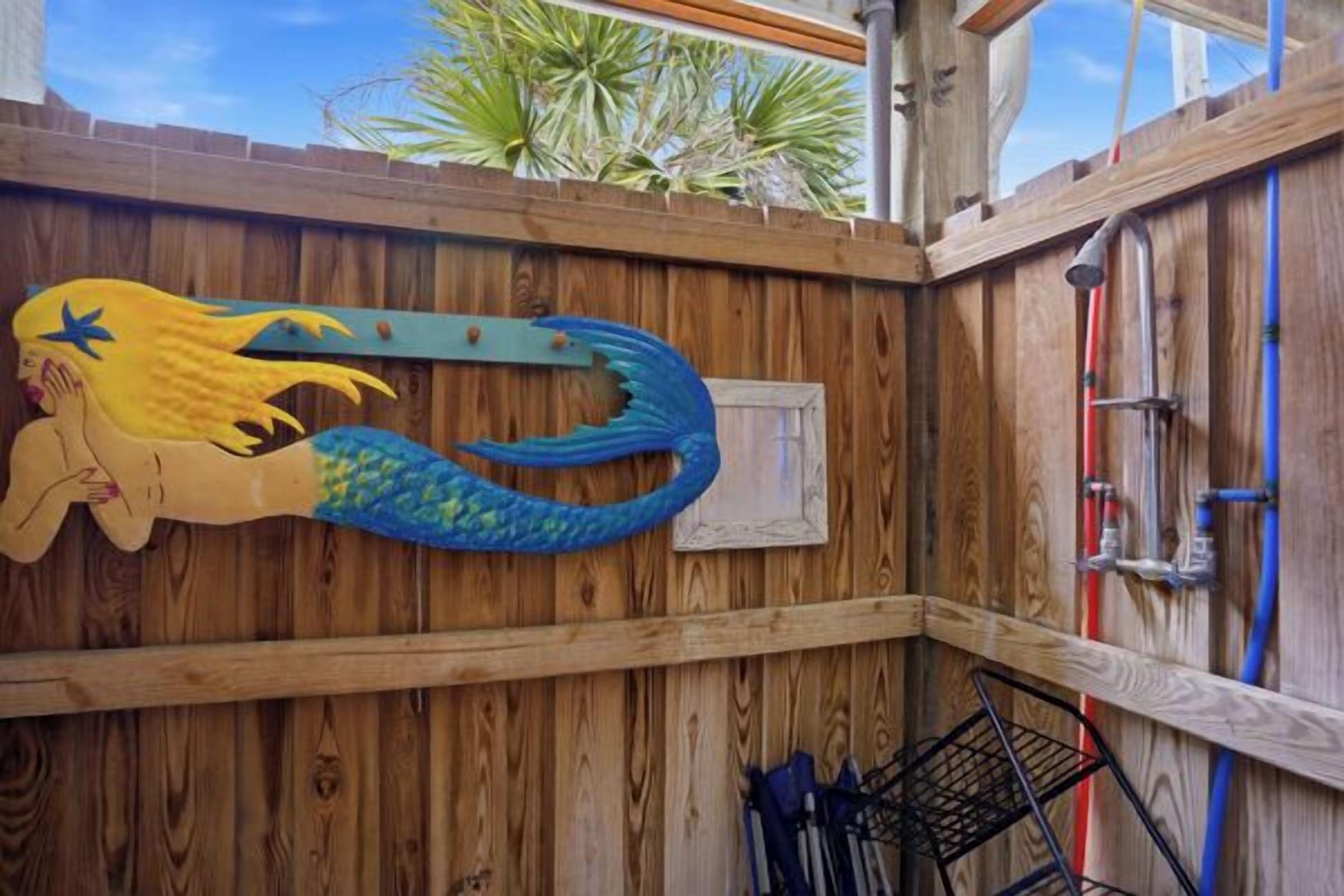 A wooden fence with a decorative mermaid tail and a metal gate.