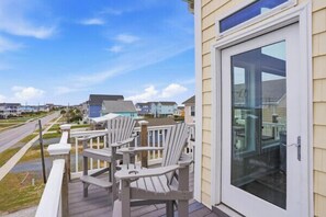 A deck with chairs, a glass door, and a view of houses. - Townhome w/ Pool & Water Views/ Sleeps 12 (Surf City)