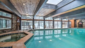 An indoor swimming pool with a wooden ceiling, stone walls, and large windows. - Spacious Retreat | Pool, Beach club,Sauna & Golf (Bellaire)