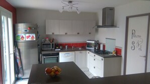 A compact kitchen with white cabinets, a stainless steel refrigerator, a microwave, a stove, and a sink.