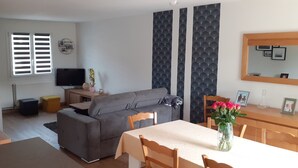 A compact living space with a sofa, dining table, and a TV.