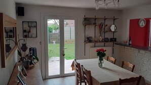 A modern kitchen with a dining area, featuring a sliding glass door to the backyard, a built-in brick wall, and a red accent wall.