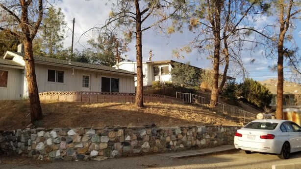 A residential area with a stone wall, a white car, and houses with a sloped roof and a visible garage. - 3BR Panoramic lake view, Lake Isabella High Speed WIFI easy access paved road (Wofford Heights)