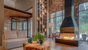 Una sala de estar moderna con chimenea, un sofá, una mesa de centro con plantas y una pared de piedra con estanterías.