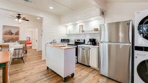 A modern kitchen with white cabinetry, stainless steel appliances, and a central island.