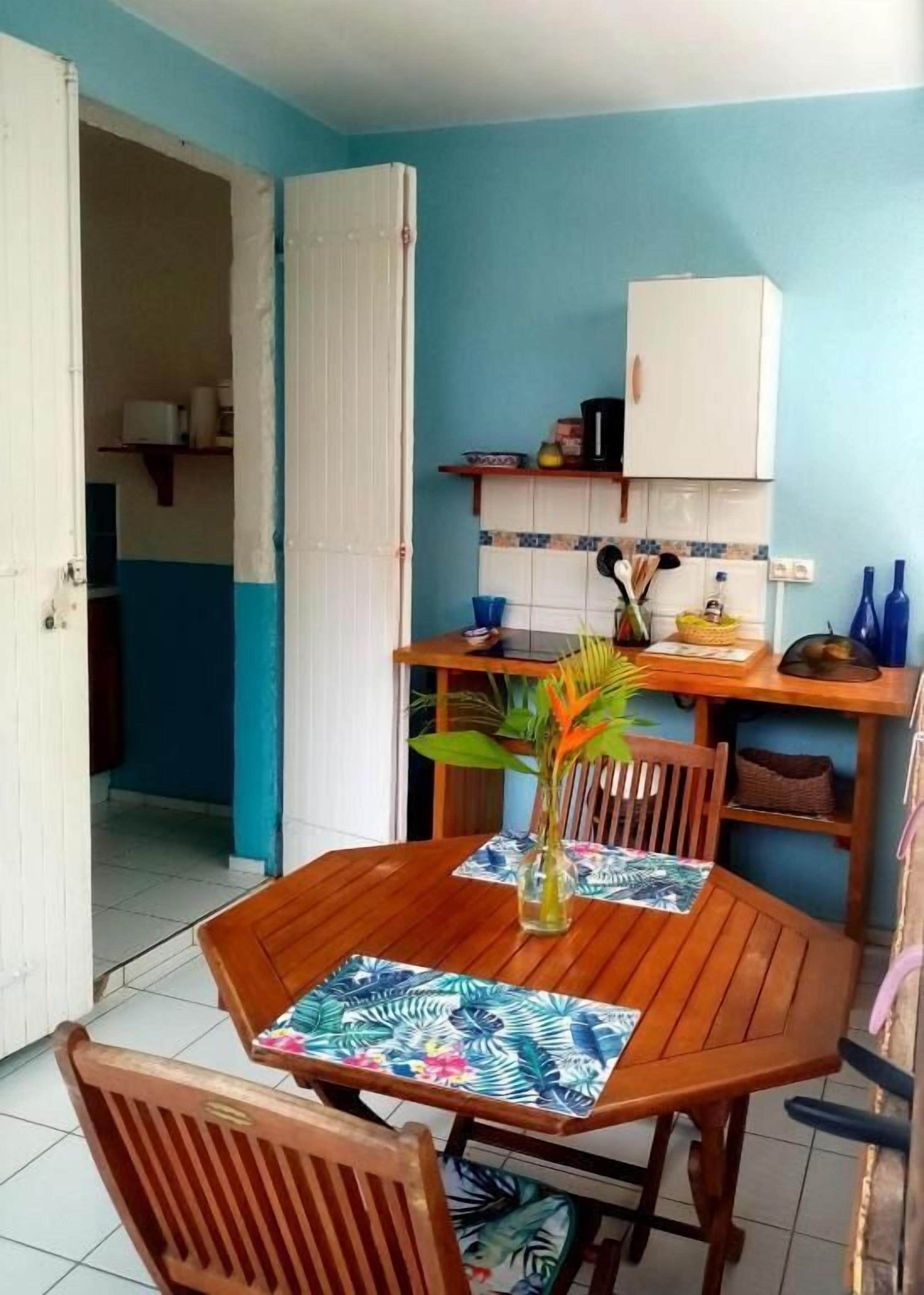 Un coin repas avec une table et des chaises en bois, un buffet blanc et un mur bleu.