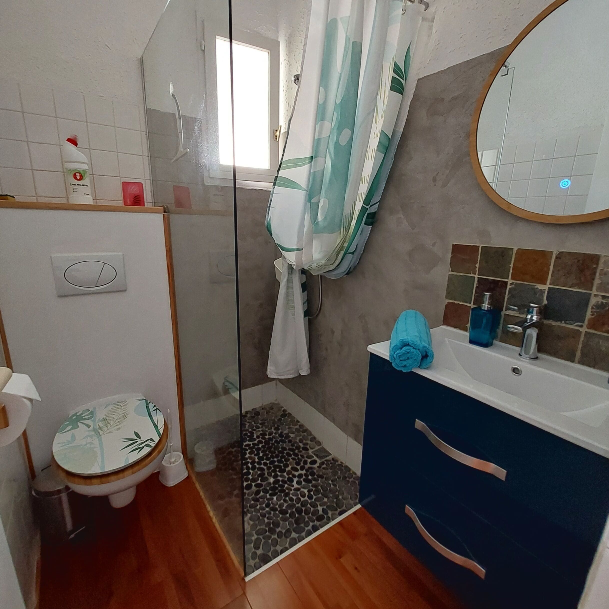 Een badkamer met douche, toilet en wastafel.