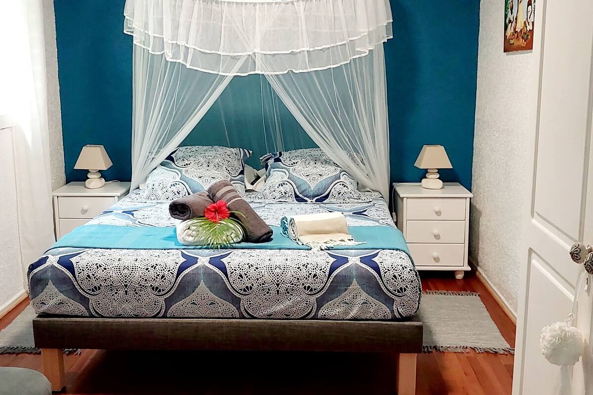 A neatly arranged bedroom with a bed, two bedside tables, a nightstand, and a mirror.