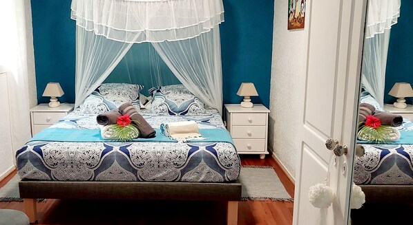 Une chambre à coucher bien rangée, avec un lit, deux tables de chevet, une commode et un miroir.