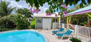 Un espace piscine avec des chaises longues et un petit bâtiment doté d’un toit végétalisé.