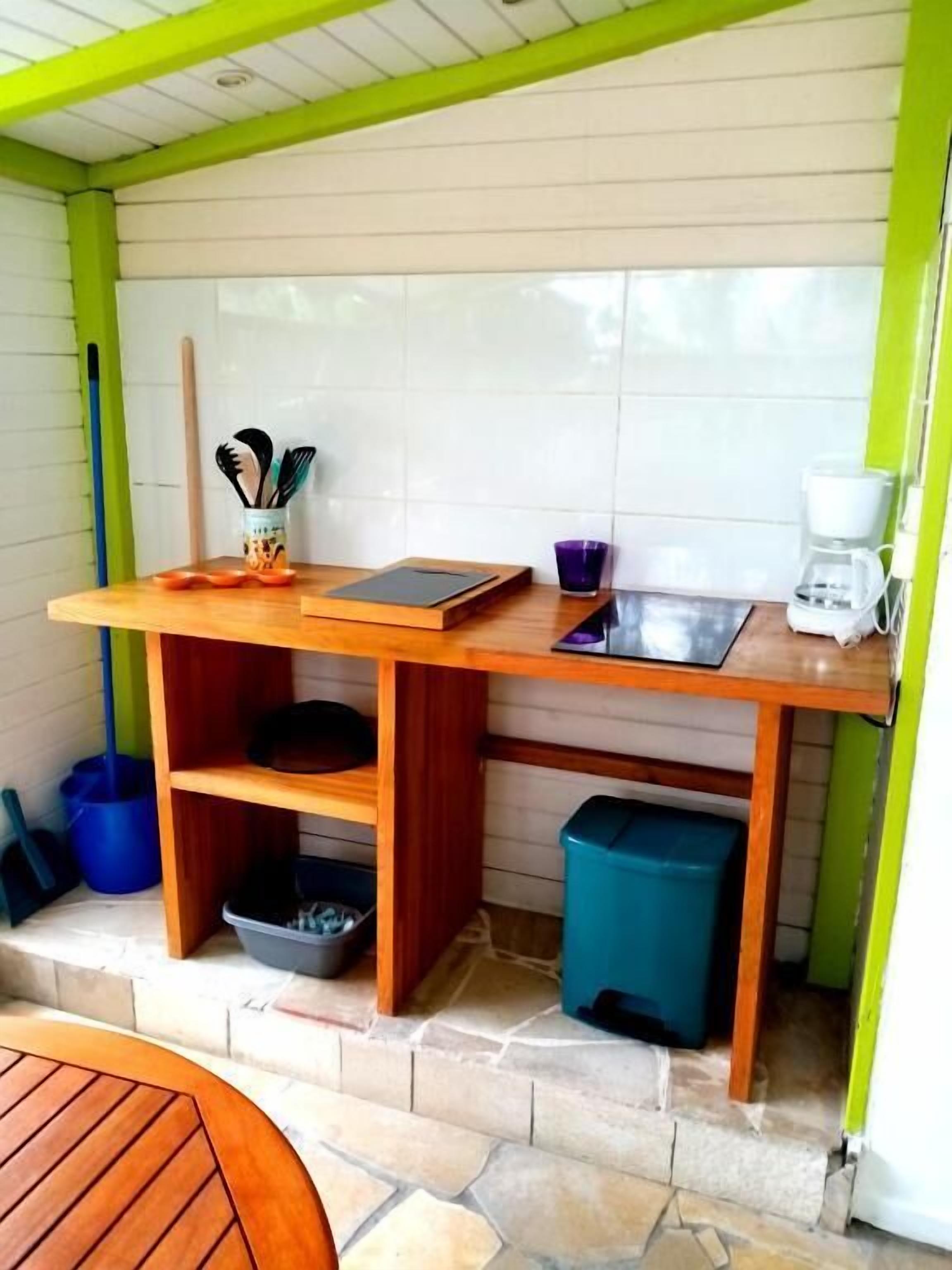 A compact kitchen with a wooden countertop, a coffee maker, and a trash bin.