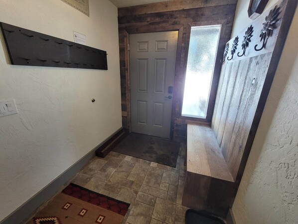 Un pasillo estrecho con una puerta de madera, una ventana pequeña y una placa en la pared.