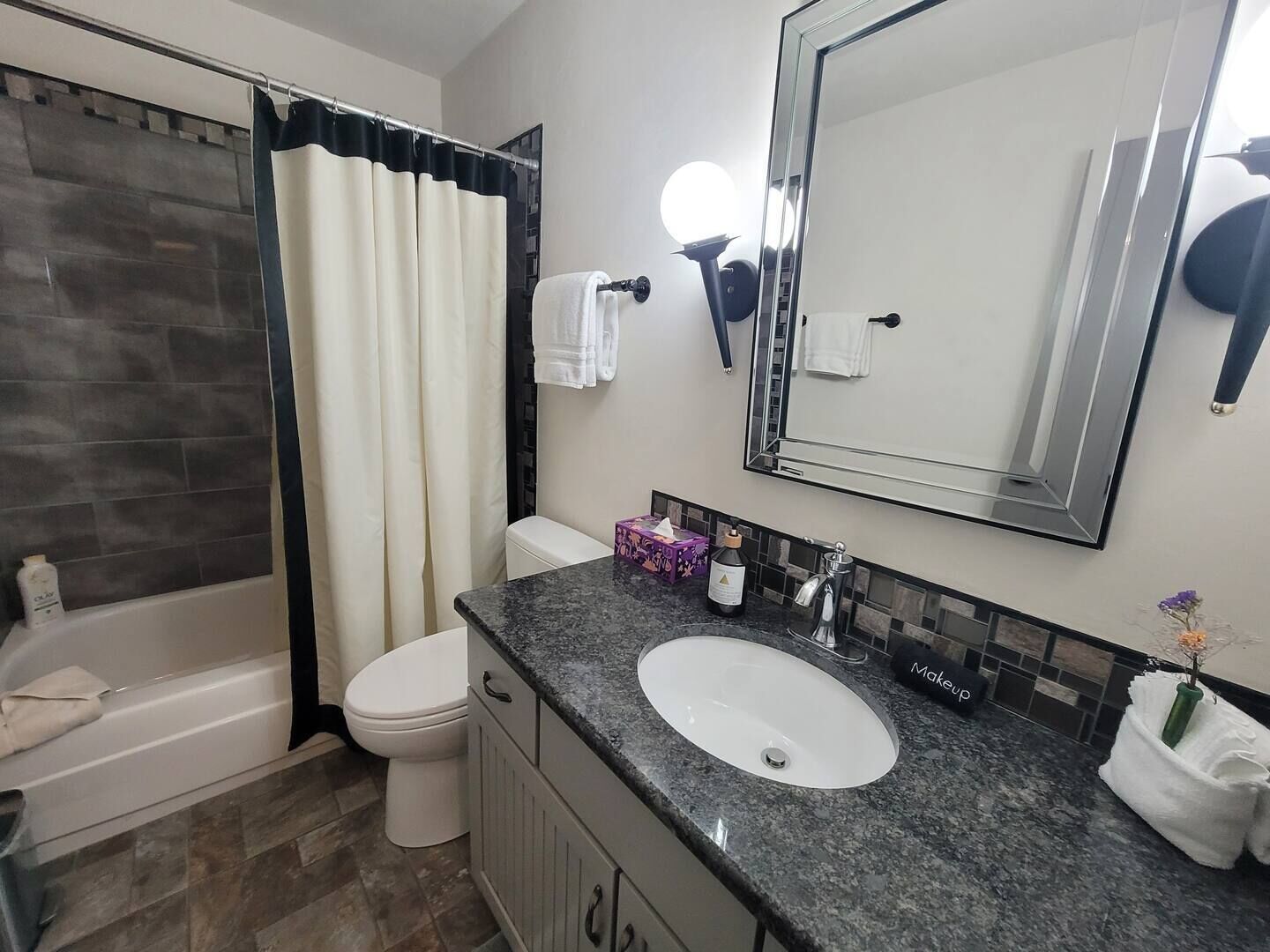 A bathroom with a bathtub, toilet, sink, and a large mirror.