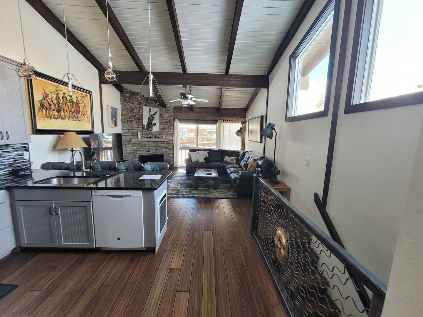 A spacious living area with a kitchen, wooden flooring, and a large window providing natural light.