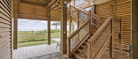 Eine Holztreppe führt zu einer oberen Ebene mit Blick auf eine grüne Landschaft.