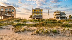 Een object aan het strand met meerdere gebouwen, waaronder een geel huis met balkon en een groter gebouw met een balkon.