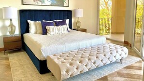 A modern bedroom with a large bed, a tufted bench, and a view of the outdoors. - Peninsula 12, 𖠁 3Bdr Lux Beach condo 𖠁Pools 𖠁Rooftop 𖠁Gym 𖠁 (Playa Langosta)