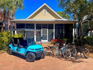 A house with a garage, a blue golf cart, and bicycles parked outside.