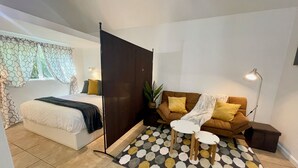 Et moderne soveværelse med seng, sengebord og sofa med et mønstret tæppe.