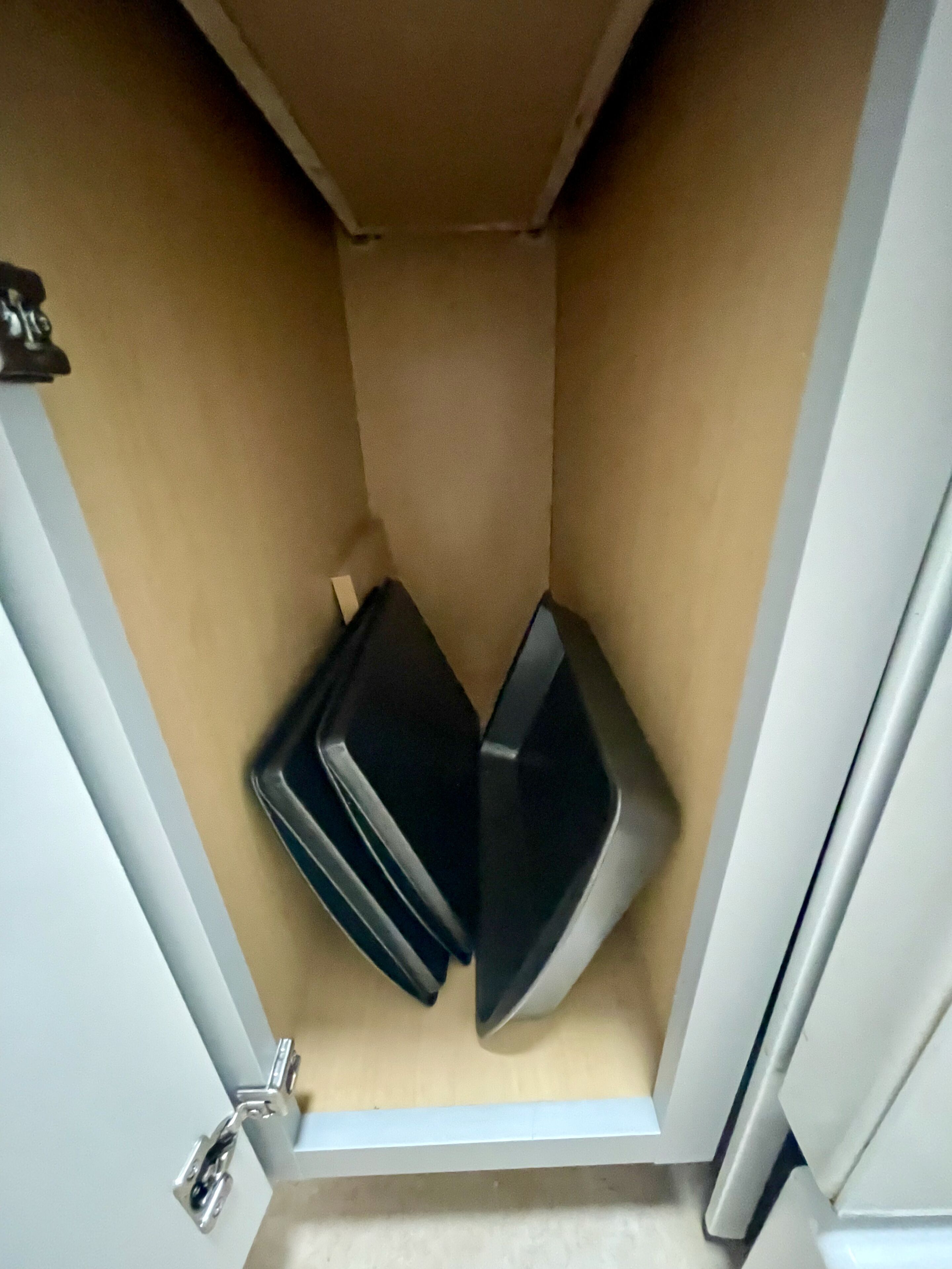A corner of a room with a white door, beige walls, and a white floor.