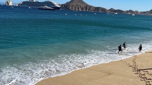 A beach with a cruise ship in the background and a rocky island.