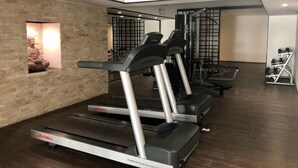 Ein Fitnessstudio mit Laufbändern, Kraftgeräten und einer Ziegelwand mit einer Statue.