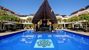 Ein Pool mit einer zentralen Struktur, umgeben von Liegebereichen und Palmen.