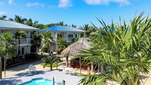 Un complexe hôtelier doté d’une piscine, d’un espace extérieur aménagé et d’une structure à toit de chaume.