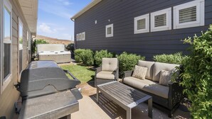 A patio with a grill, a sofa, and a chair. - New | 4 Bed | Heated Pool | Lazy River | Mini Golf | BI (Washington)