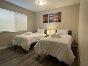 A hotel room with two beds, a large window with blinds, and two wall-mounted paintings. - Entire House 30+days 4 Bedrooms Central Located (Las Vegas)