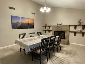 A dining room with a long table, chairs, a chandelier, a fireplace, and wall art. - Entire House 30+days 4 Bedrooms Central Located (Las Vegas)