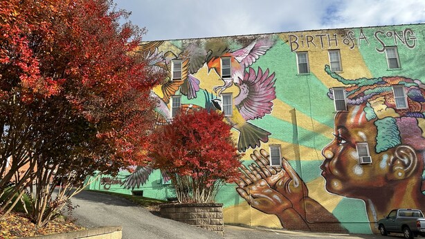 A mural on a building with the text "Birth of a Song" and a bird.