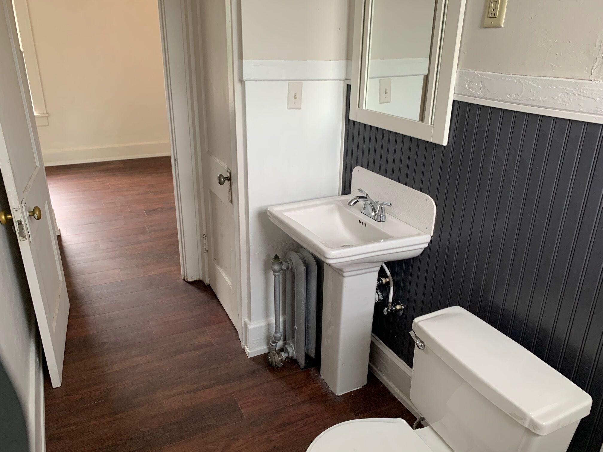 A bathroom with a white sink, toilet, and radiator.