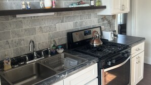 A kitchen with a marble backsplash, stainless steel appliances, and white cabinetry.