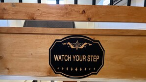 A wooden sign with the text "WATCH YOUR STEP" in a room with a sofa and a coffee table. - The Archer House - 1 Block from Spring River.  2 Bedrooms + Loft Bedroom!   (Mammoth Spring)