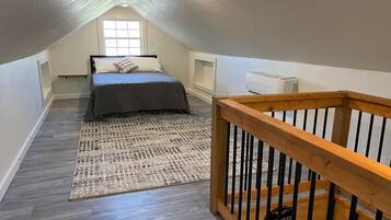 Une chambre à coucher avec un lit, un tapis, une rambarde en bois et une fenêtre.