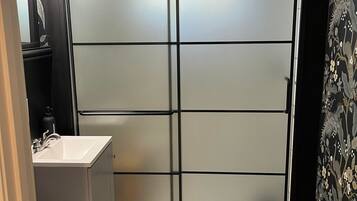 A bathroom with a modern design, featuring a toilet, sink, and a shower area with frosted glass doors.