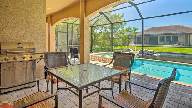 Une terrasse extérieure équipée d’un barbecue, de sièges et offrant une vue sur une piscine.