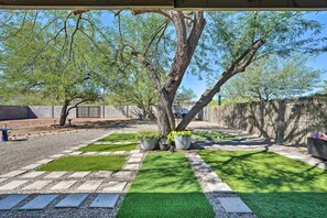 Stroll through a serene outdoor space with a paved walkway, lush greenery, and a majestic tree providing shade.