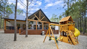 Uma cabana com um deck espaçoso e um parquinho.