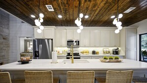 Uma cozinha moderna com armários brancos, eletrodomésticos de aço inoxidável e uma ilha grande com banquetas.
