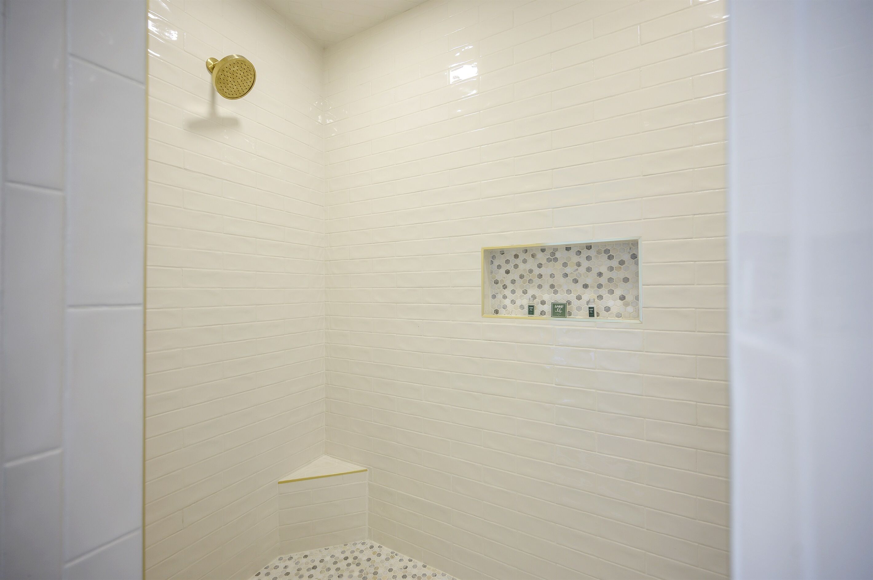 Ducha con paredes de azulejos blancos y cabezal de ducha.